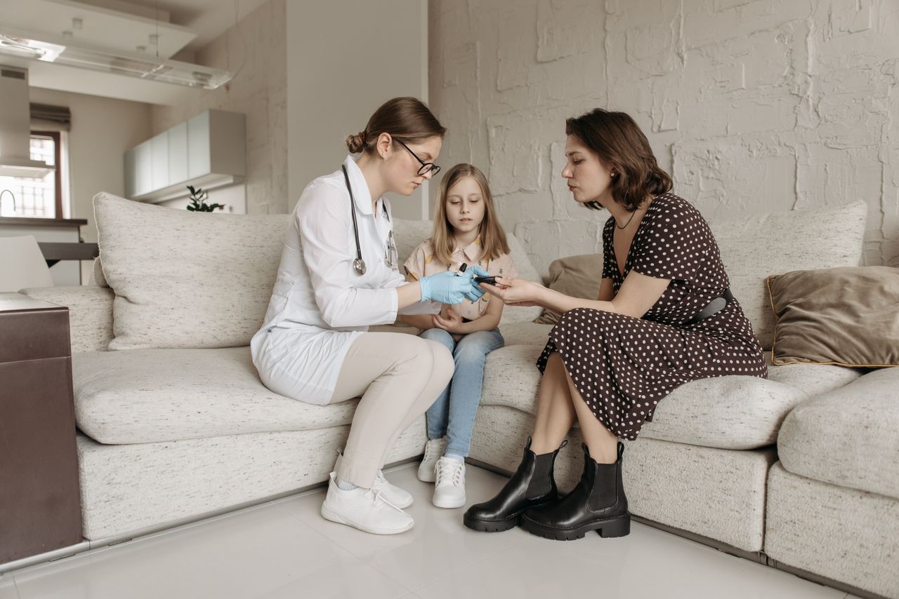 Services A medical professional examines a child's hand while the mother watches closely.
